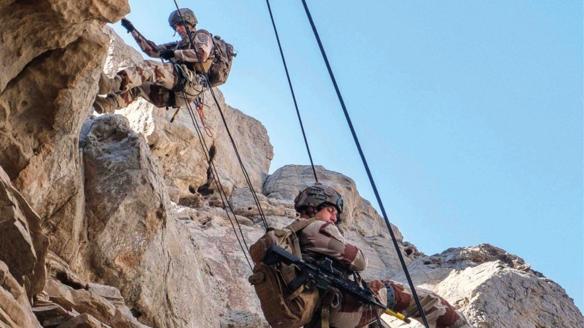  Deux chasseurs alpins descendent une paroi rocheuse en rappel.