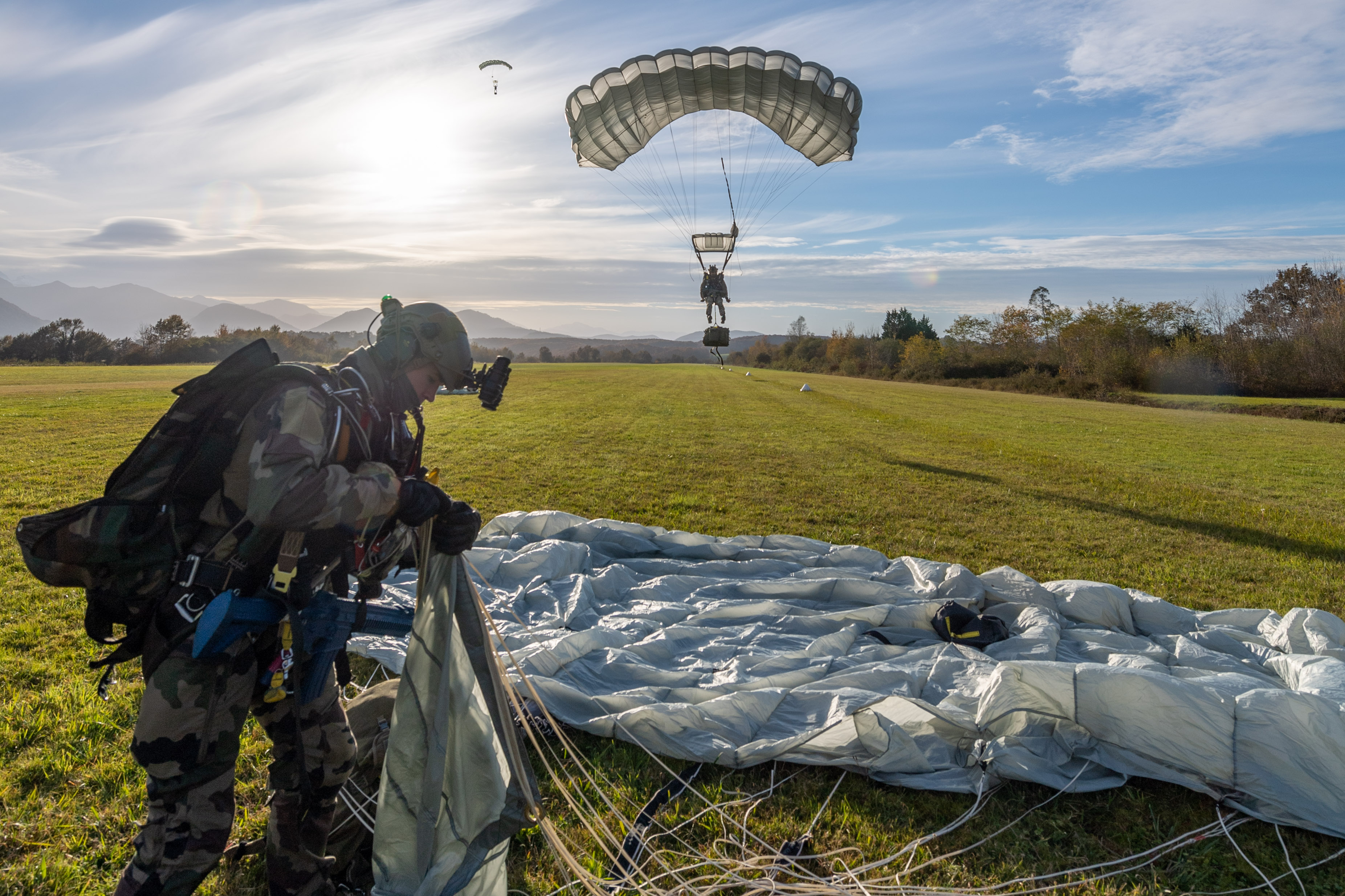 Au sol, les équipes replient rapidement leurs parachutes. Leur mission à terre commence.