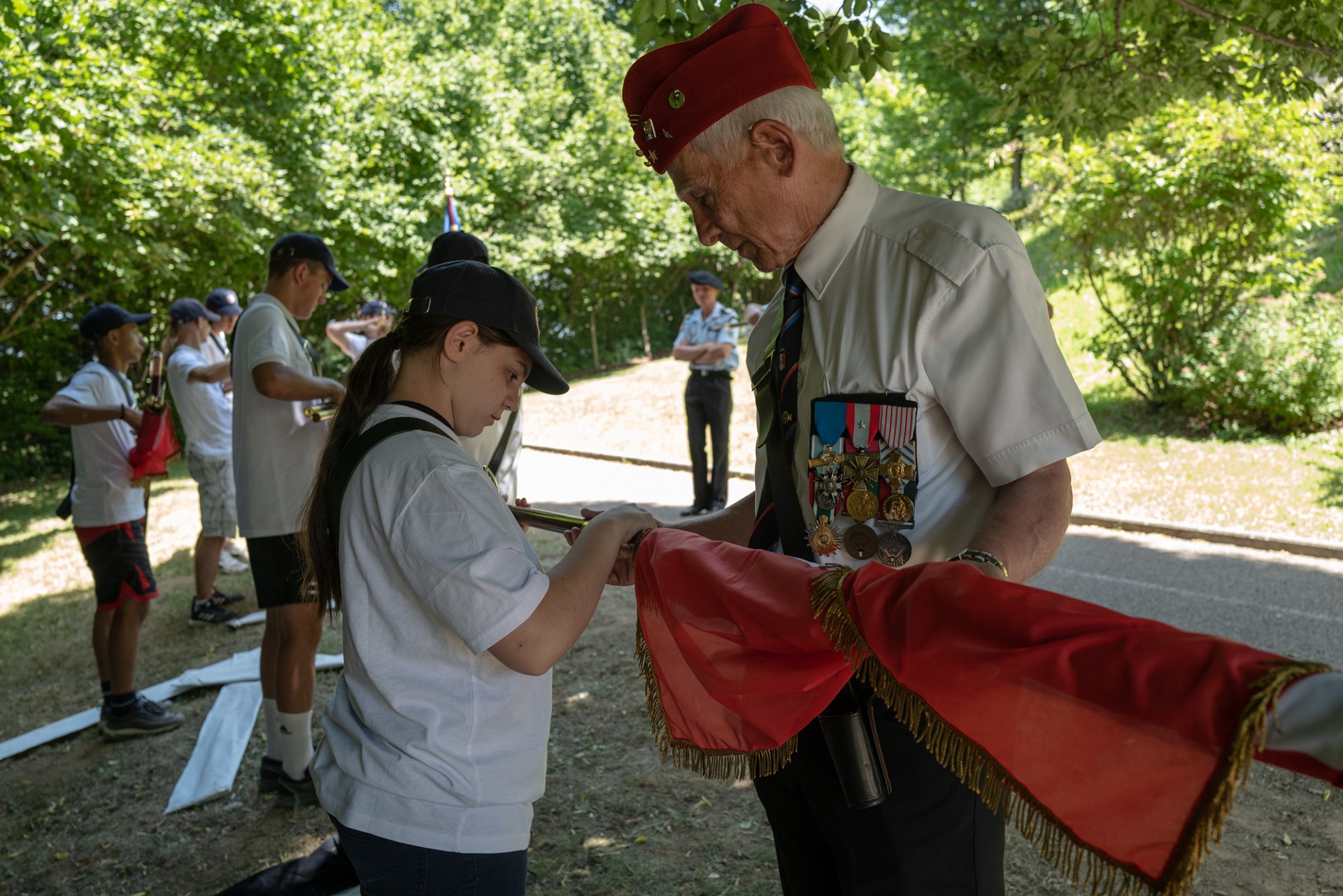 Un ancien confie un drapeau à un jeune.