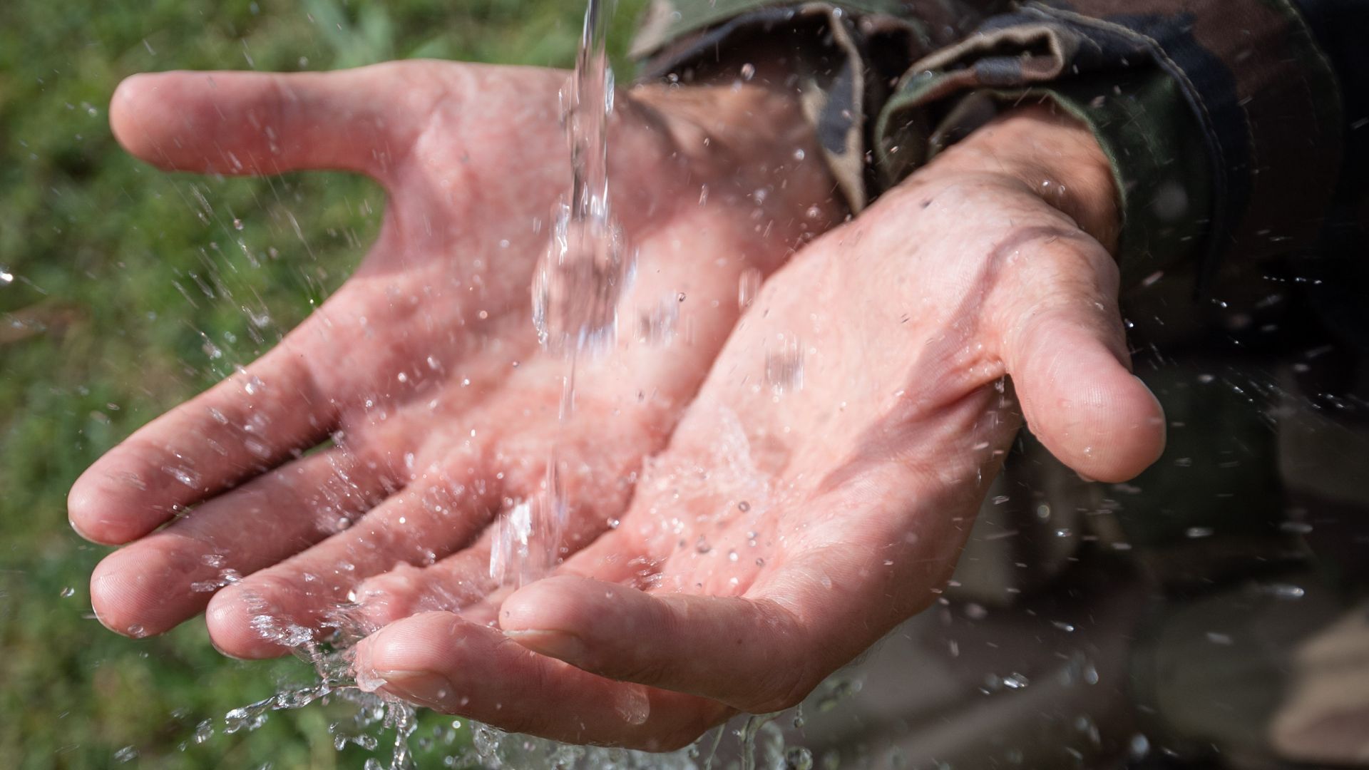 Un militaire reçoit de l'eau dans ses mains, symbole de l'énergie