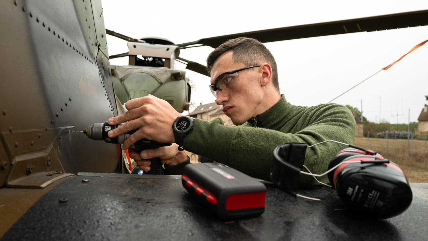 Perçeuse à la main, un mécanicien structure effectue un acte de maintenance sur le fuselage d'un hélicoptère Tigre.