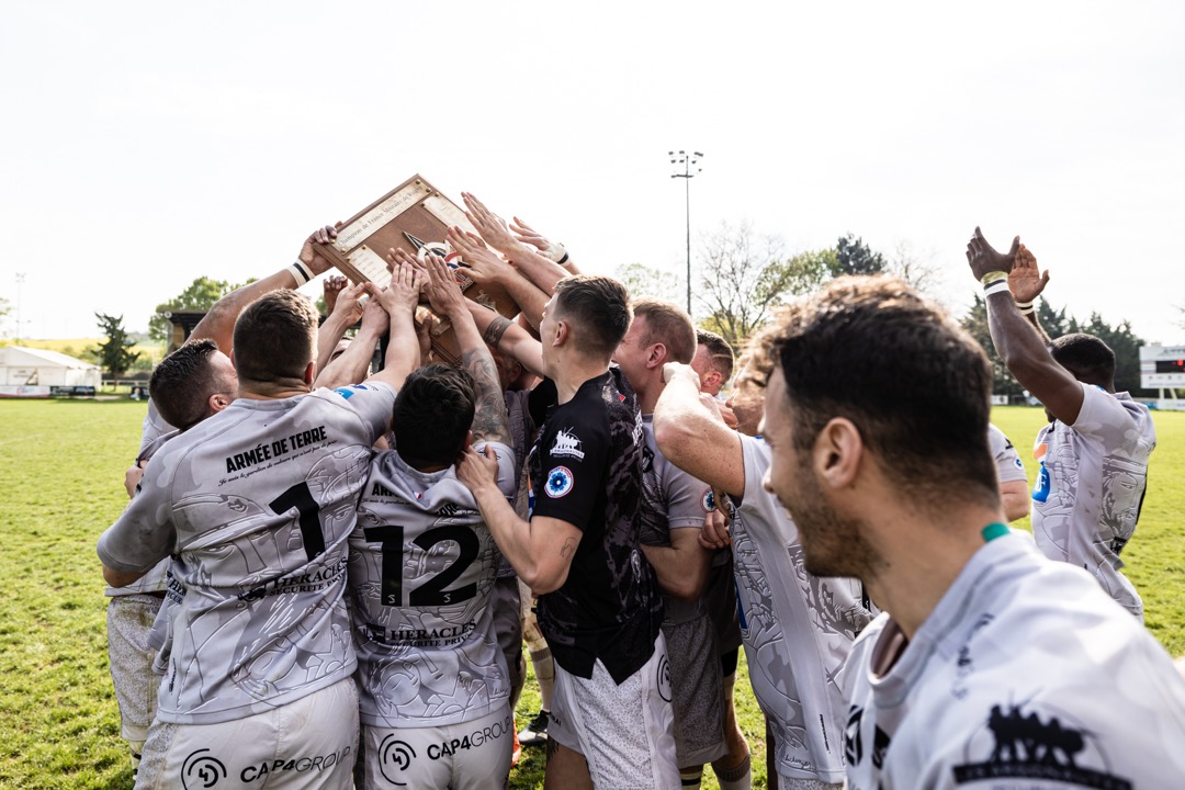 La sélection de rugby à XV touche le bouclier, symbole de sa victoire au championnat de France militaire 2023.