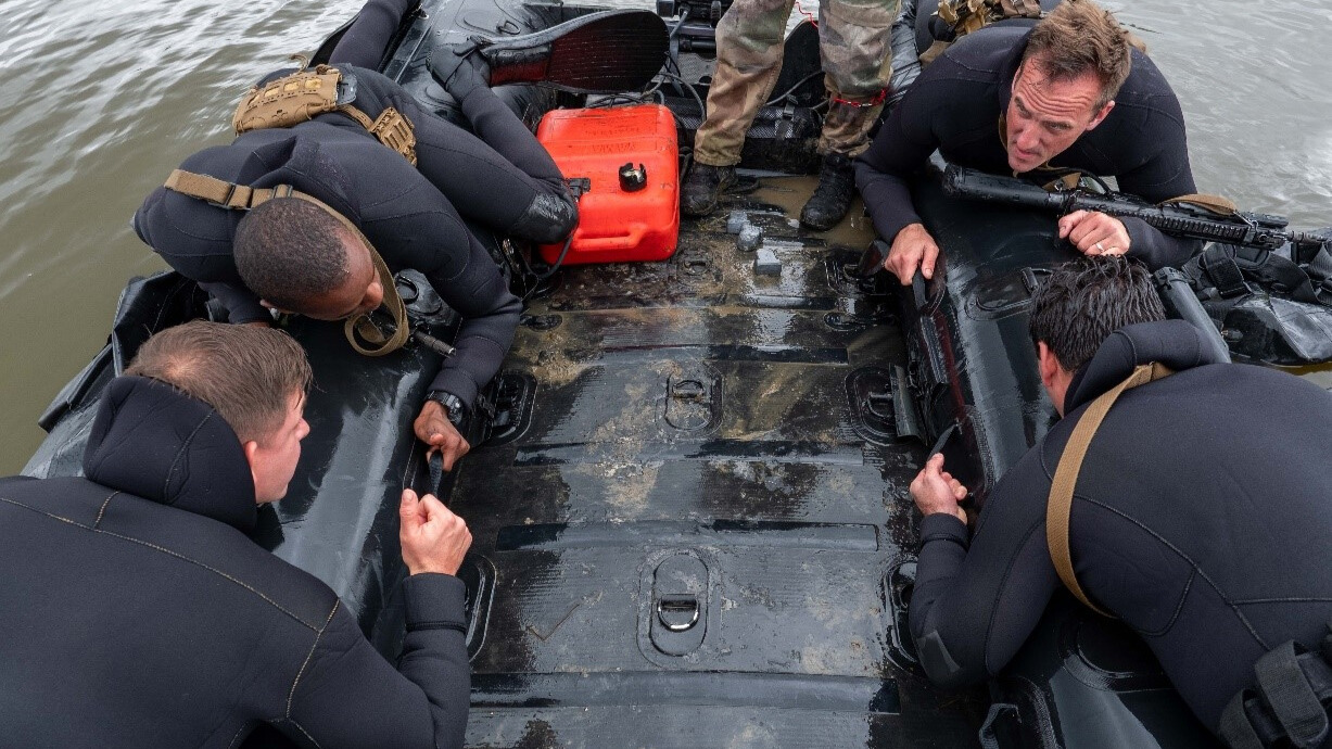 Les soldats du GAE-A se trouvent sur les bords du bateau, prêts à entrer dans l'eau. 