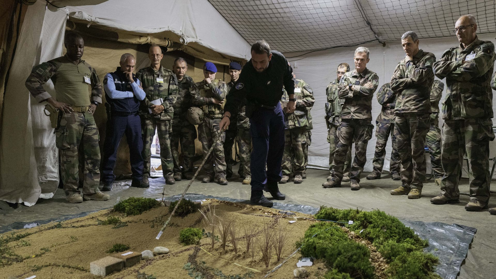 Les chefs militaires et gendarmes déroulent l’opération du lendemain sur une caisse à sable, représentant le baptême terrain. 