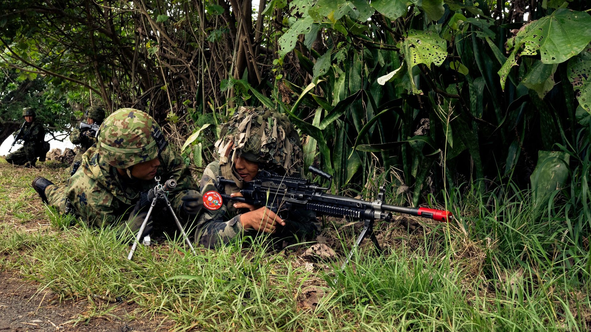 Un soldat japonnais et français, allongés au sol, échangent lors d'une phase de tir.