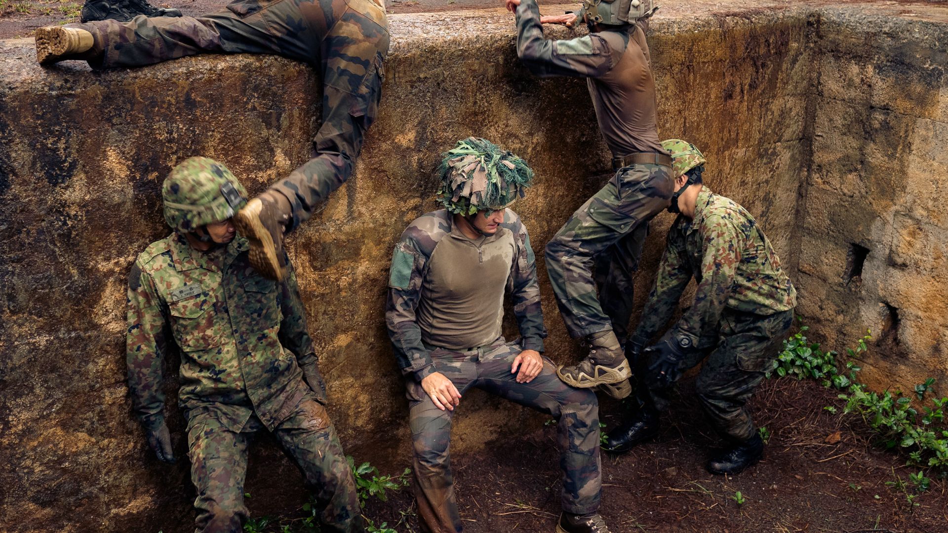 Des soldats japonais et des légionnaires du 2e REI dans la fosse du parcours d'obstacle.