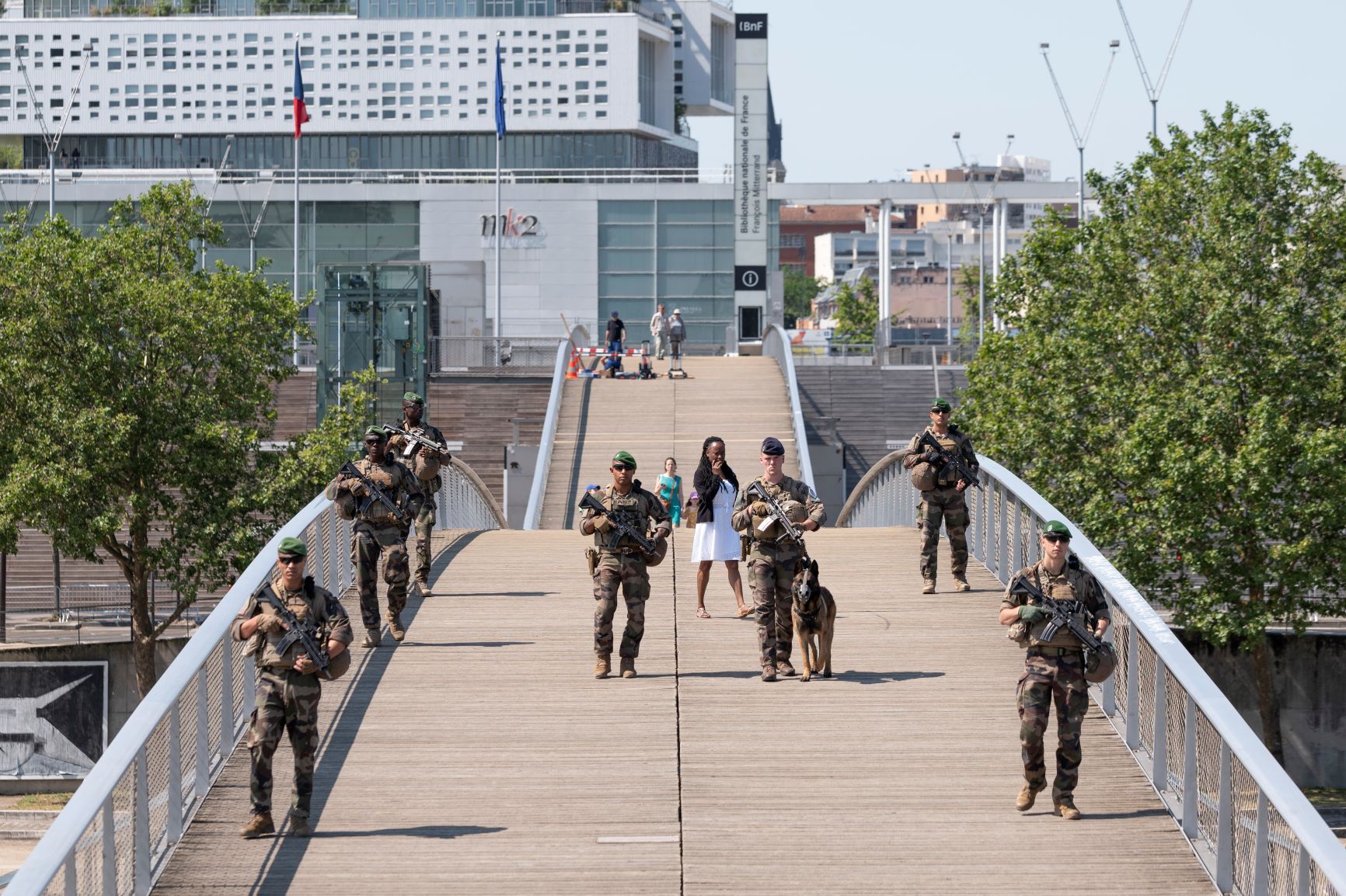 Une patrouille composée de légionnaires du 1er régiment étranger de cavalerie et d'une équipe cynotechnique du 132e régiment d'infanterie cynotechnique empruntent la passerelle Simone de Beauvoir enjambant la Seine.